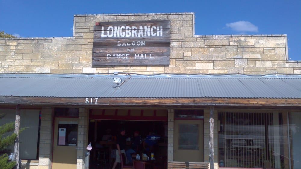 The limestone Longbranch Saloon & Dance Hall sign above the storefront at 817 N Main