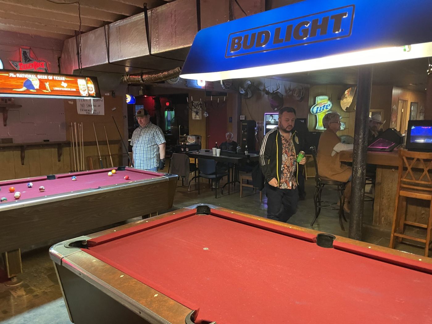 Red-felt pool tables under a Bud Light lamp